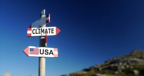 Climate change and American flag in two directions on road sign. Withdrawal of climatic agreement. Climate change and American flag in two directions on road sign. Withdrawal of climatic agreement.
