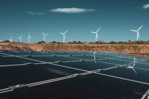 Wind farm and solar panels under a beautiful blue sky with a few clouds. Renewable energy generation for environmental conservation concept. zones d'accélération des énergies renouvelables