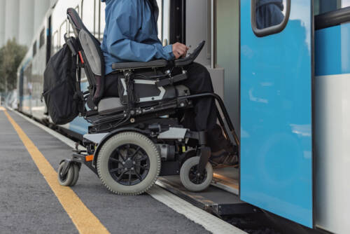 Man with a physical disability, an electric wheelchair user entering a train Man with a physical disability, an electric wheelchair user entering a train